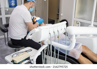 Practitioner Male Dentist Drilling Tooth To Patient In Dental Studio