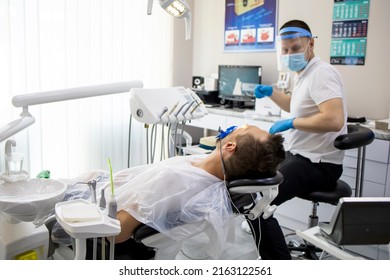 Practitioner Male Dentist Drilling Tooth To Patient In Dental Studio