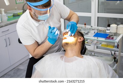 Practitioner Male Dentist Drilling Tooth To Patient In Dental Studio