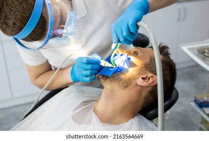 Practitioner Male Dentist Drilling Tooth To Patient In Dental Studio