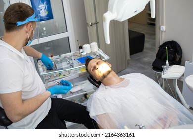 Practitioner Male Dentist Drilling Tooth To Patient In Dental Studio