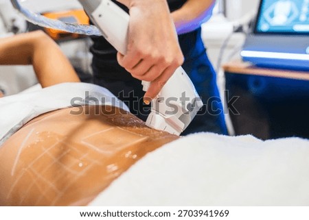 Practitioner performing High Intensity Focused Ultrasound procedure on a person's abdomen, applying non invasive body contouring and skin lifting treatment with gel
