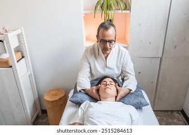 A practitioner provides craniosacral therapy by holding the patient head in a calm, serene environment. Concept of healing energy and balance. - Powered by Shutterstock