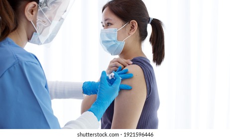Practitioner vaccinating woman patient in clinic. Doctor giving injection to adult woman at hospital. Nurse holding syringe and inject Covid-19 or coronavirus vaccine.Injection covid vaccine concept.