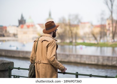 Prague, Czech Republic. 09-23-2019. Man giving the back to the camera watching the Vltava river while walking and enjoying close to the Charles Bridge during a sunny day in Prague. - Shutterstock ID 1896907360