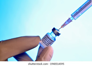 PRAGUE, CZECH REPUBLIC - March 21, 2021: COVID-19 SARS virus vaccine ampoule. COMIRNATY mRNA vaccine on white blue backround. Syringe with COMIRNATY vaccine against SARS COVID-19 virus.
