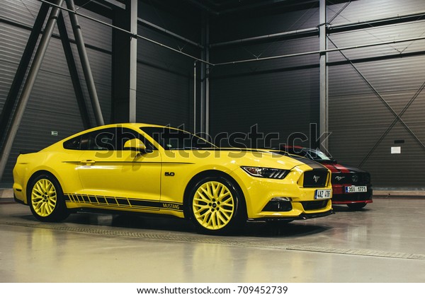 PRAGUE, CZECH REPUBLIC\
- SEPTEMBER 3rd 2017: Yellow Ford Mustang with black one behind it\
in on display in a hall during Prague Car Festival on 3rd September\
2017 in Prague, CZE.