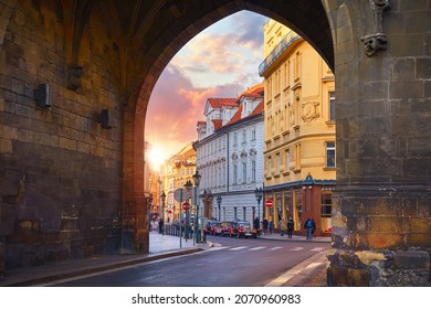 Prague, Czech Republic. Sunset in old town through medieval arch in Powder Gate tower of vintage european street. Scenic urban landscape with sun.