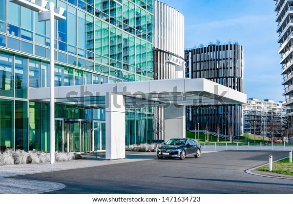 Prague, The Czech Republic,2.8.2019: Luxury car\
parks in front of business center. Modern glass skyscraper business\
centre with luxury car on\
parking.