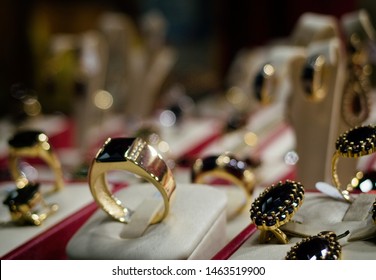 Prague, Czechia - April 5, 2017: Golden Wedding Rings With Bohemian Garnet In The Jewelry Store Shop. Detail Of Many Wedding Rings In Shop Window Of Luxury Goldsmithery. Rings Store Close Up.