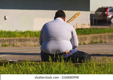 Prague, Czechia -  Jun 2, 2017: Fat Man From Behind Sitting On The Street Park. An Obese Man Sitting In A City Park. Concept Of Unhealthly Life Style. Obesity Causes Civilization Diseases.