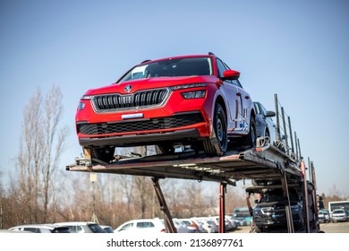 PRAGUE, CZECHIA – MARCH 11, 2022: New Red Škoda Kamiq Crossover - SUV On Car Carrier Trailer, Car-carrying Trailer, Car Hauler, Auto Transport Trailer, Semi-trailer. Front View Car. Rear View Trailer.