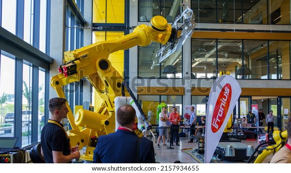 Praha, Czech republic - May 18 2022: Robotic\
equipment fair at Fanuc robots in the showroom. Handling arm.\
Massive handling arm with car body\
parts.