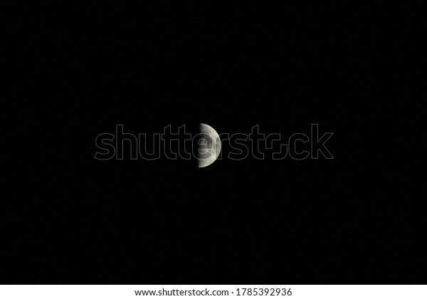 PRAHOVA COUNTY, ROMANIA-JULY 27, 2020: The moon\
is in it\'s first quarter phase, being lighter than before and its\
craters being visible