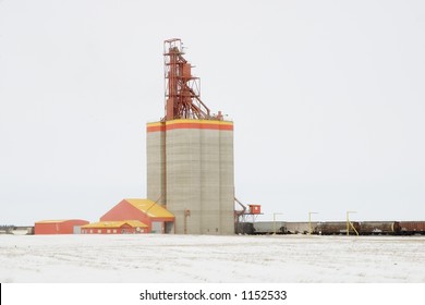 A prairie grain elevator filled with wheat and a train waiting to be loaded.