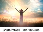 Praise and worship God concept: Silhouette of healthy woman raised hands at meadow sunset background