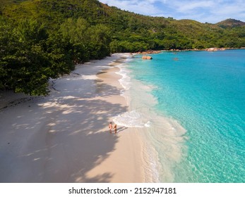 Praslin Seychelles tropical island with withe beaches and palm trees, couple of men and women mid age on vacation at Seychelles visiting the tropical beach of Anse Lazio Praslin Seychelles. 
