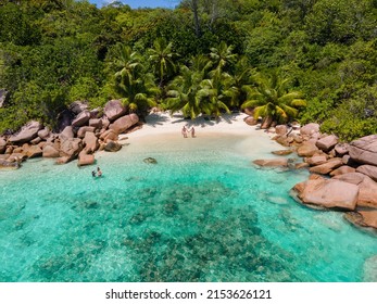 Praslin Seychelles tropical island with withe beaches and palm trees, couple of men and women mid age on vacation at Seychelles visiting the tropical beach Anse Lazio Praslin Seychelles. drone view 