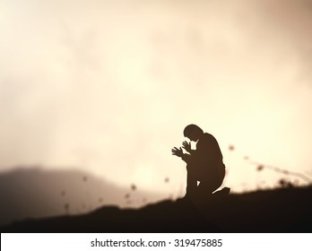 Pray Concept: Humble Man Kneeling To Praise And Worship God On Mountain Sunset Background