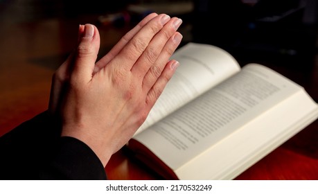 Pray to God, faith, religion and spirituality concept. Prayer, woman hands over an open Holy Bible book, wooden desk background.