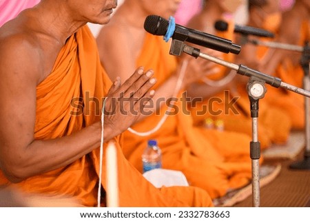 Pray of monks edify with the microphone on ritual Buddhist ceremony. Line of Buddha monk sit on carpet to pray for Buddhism. 