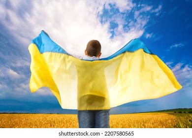 Pray For Ukraine. Boy With Ukrainian Flag In Wheat Field. Little Kid Waving National Flag Praying For Peace. Happy Child Celebrating Independence Day.