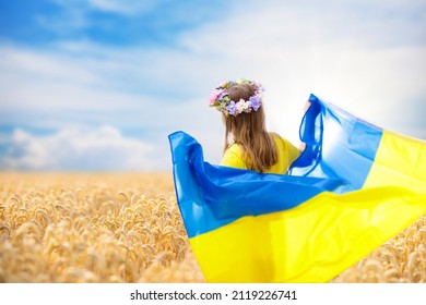 Pray for Ukraine. Child with Ukrainian flag in wheat field. Little girl waving national flag praying for peace. Happy kid celebrating Independence Day.