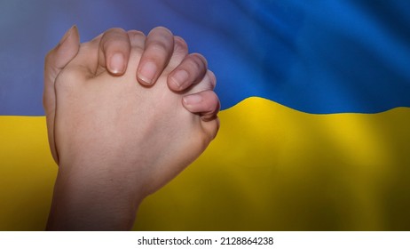 Pray for Ukraine message with a hand in prayer and the Ukrainian flag in the background.