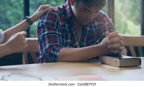 Prayer And Bible  In Christian Religion Concept. Asian Man And Woman Praying, Hope For Peace And Free From War And Coronavirus, Hand In Hand Together, Believes And Faith At Church