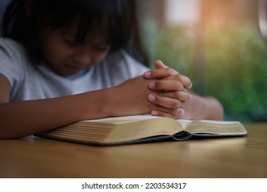 Prayer And Bible Concept. Asian Kid Praying, Hope For Peace And Free From War And Coronavirus, Hand In Hand Together By Child. Little Girl Believes And Faith In Christian Religion At Church.