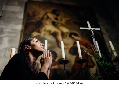 Prayer for deceased.Religious woman praying for health and healing to God in church.Woman in emotional stress,pain,fear.Memory of a loved one.Christianity.Strong religion,faith and hope concept