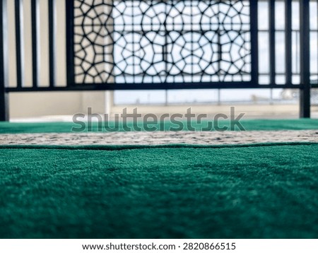 The prayer direction indicator is located at the top end of the prayer mat, where the worshipper's head is placed