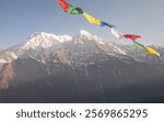 Prayer flags blowing by the wind with View of Mt.Annapurna South (7,219 m) and Mt.Hiunchuli (6,441 m) before sunrise seen from Mardi Himal view point in the Annapurna region of Nepal. 