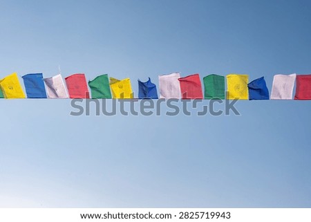 Prayer flags blowing by the wind isolated on blue sky. The prayer flags initiate peace and good tidings, their sacred mantras etched on the wind.