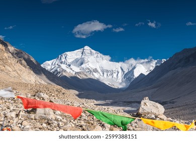 Prayer Flags blowing in the wind with Sun Flare blue sky white clouds sunny day at Mount Everest Base Camp in Tibet China