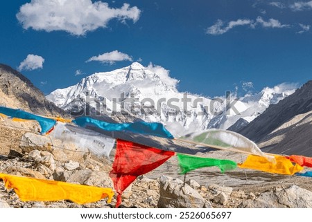 Prayer Flags blowing in the wind with Sun Flare blue sky white clouds sunny day at Mount Everest Base Camp in Tibet China