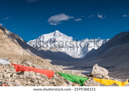 Prayer Flags blowing in the wind with Sun Flare blue sky white clouds sunny day at Mount Everest Base Camp in Tibet China