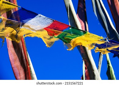 Prayer flags are waving in the wind in the Kingdom of Bhutan in the Himalaya Mountains against a blue sky in blaze of color.