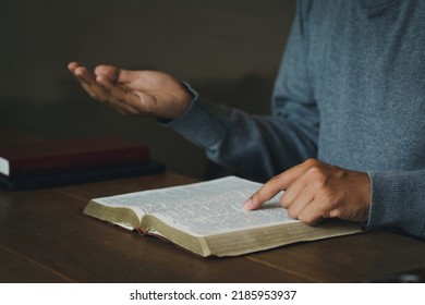 Prayer Man's Hands Folded In Prayer On A Holy Bible In Church Concept For Faith. Spirituality And Religion, Holding Hands In Prayer On A Wooden Table. Christian Life Crisis Prayer To God. 