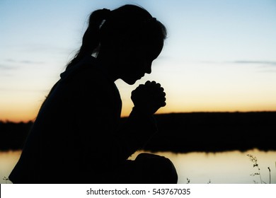 Prayer. Silhouette Girl Prays At Sunset.