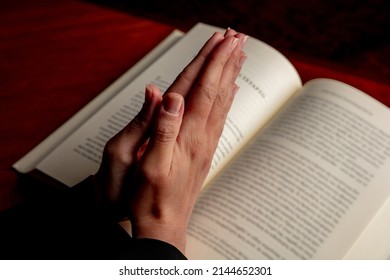 Prayer, woman hands over an open Holy Bible book, wooden desk background. Pray to God, faith, religion and spirituality concept