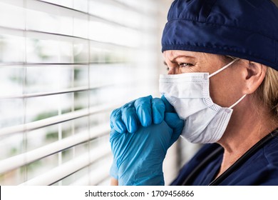 Prayerful Stressed Female Doctor Or Nurse On Break At Window Wearing Medical Face Mask.