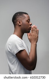 Praying african american man hoping for better. Asking God for good luck, success, forgiveness. Power of religion, belief, worship. Holding hands in prayer, eyes closed.