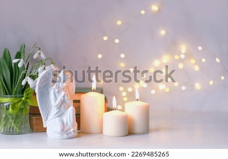 praying angel, candles, flowers and books on table, abstract light background. Christmas or Easter holiday concept. Religious church holiday. symbol of faith in God, Christianity Feast