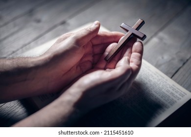 Praying with the bible and holding religious crucifix cross background
