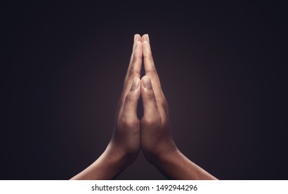 Руки молитвы с верой в религию и верой в Бога на темном фоне. Сила надежды или любви и преданности. Жест рук Намасте или Намаскара. Молитвенная позиция