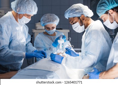 Pre oxygenation for general anesthesia. Focused surgeon team operating in an operating theatre, blue filter - Powered by Shutterstock