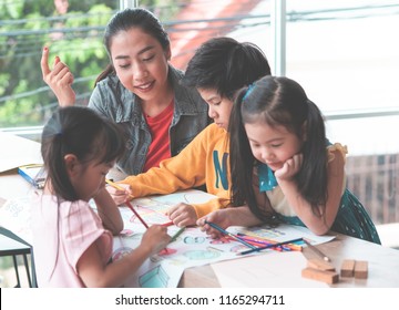 Pre School Small Student kids are painting on paper in Art group with teacher guiding them in Daycare school educational creativity concept. - Powered by Shutterstock