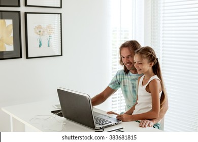 Pre Teen Daughter Came To Her Dad When He Was Using Laptop In Home Room. Father Browsing Internet With Child Together.