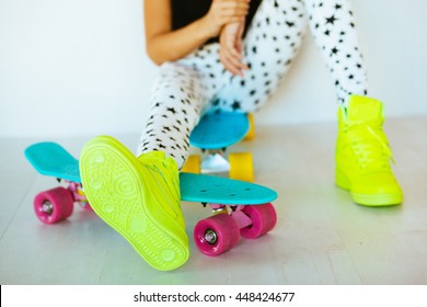 Pre Teen Girl Wearing Cool Fashion Clothing And Sneakers Posing With Colorful Skateboard Against White Wall